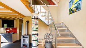 Een modern interieur met een houten trap, een keukenhoek en een decoratieve wereldbol.