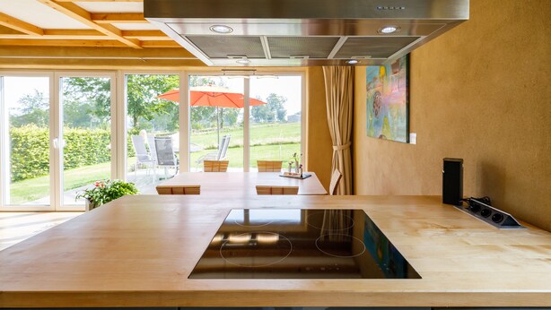 Een moderne keuken met een centraal eiland, grote ramen en uitzicht op de omgeving.
