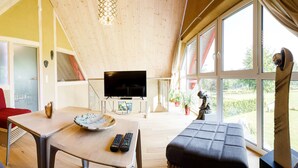 Een moderne woonkamer met een televisie, zitplaatsen en grote ramen.