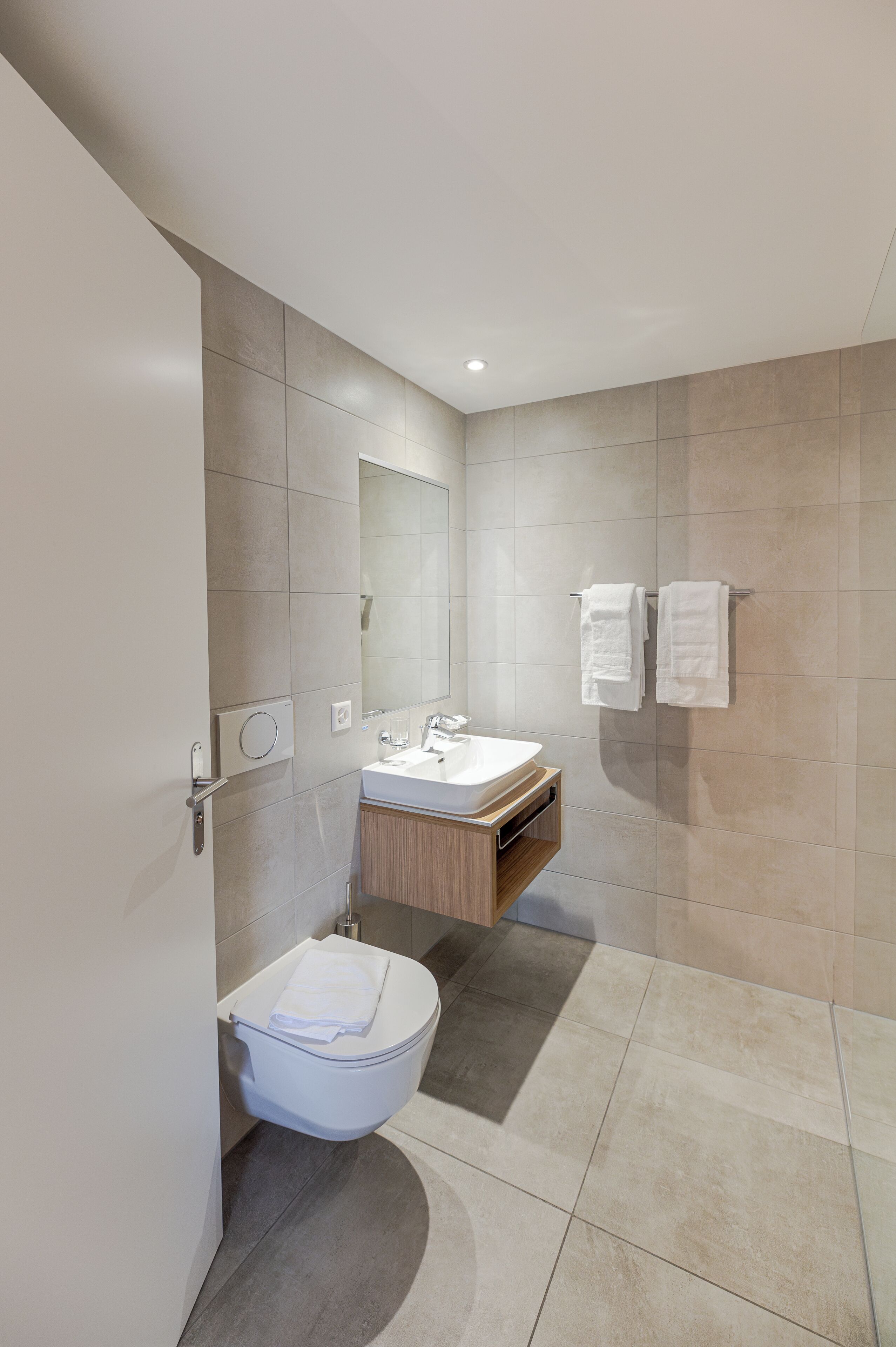 A modern bathroom with a toilet, sink, and mirror.