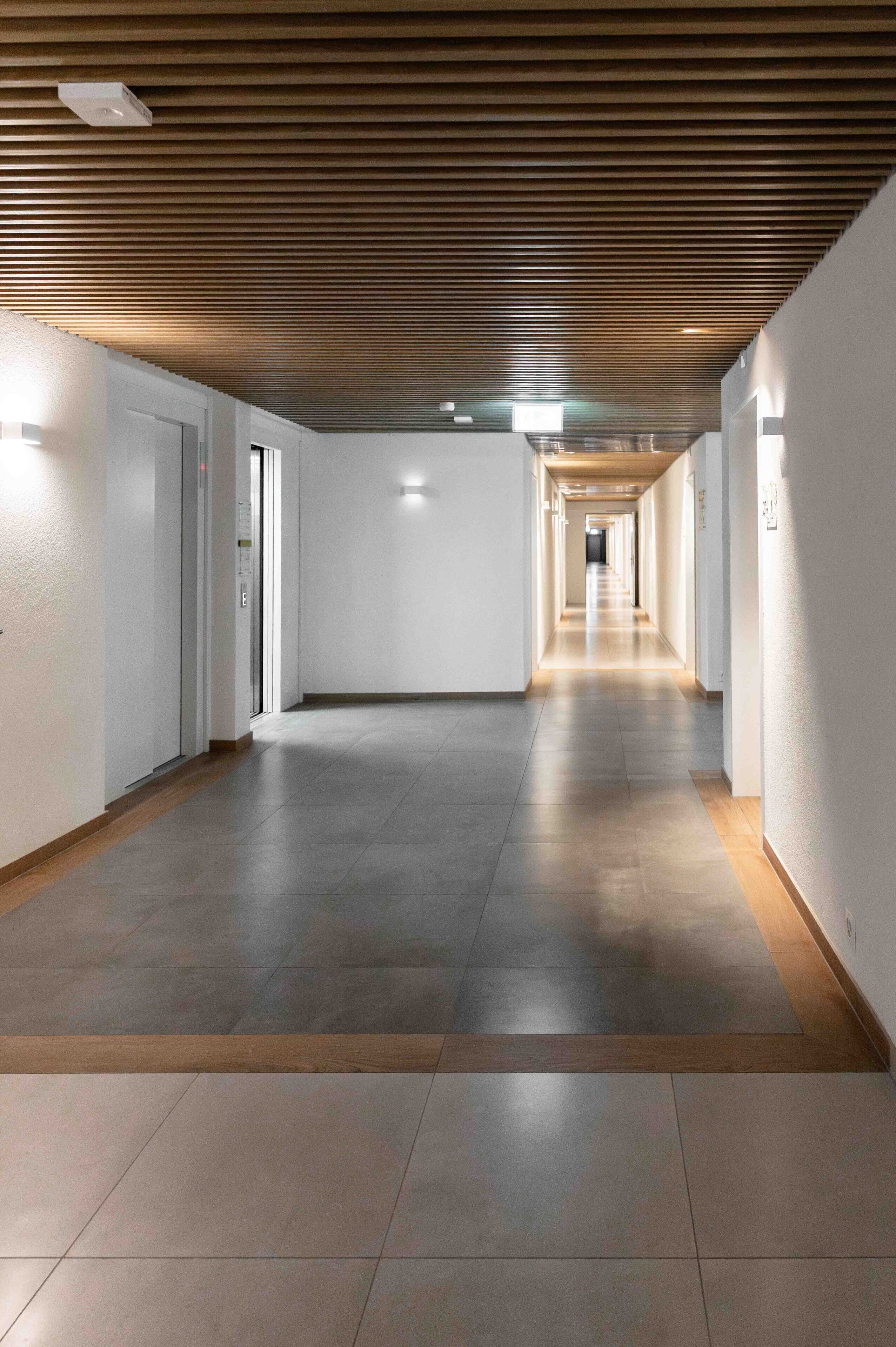 A long, narrow hallway with a wooden ceiling and tiled floors.