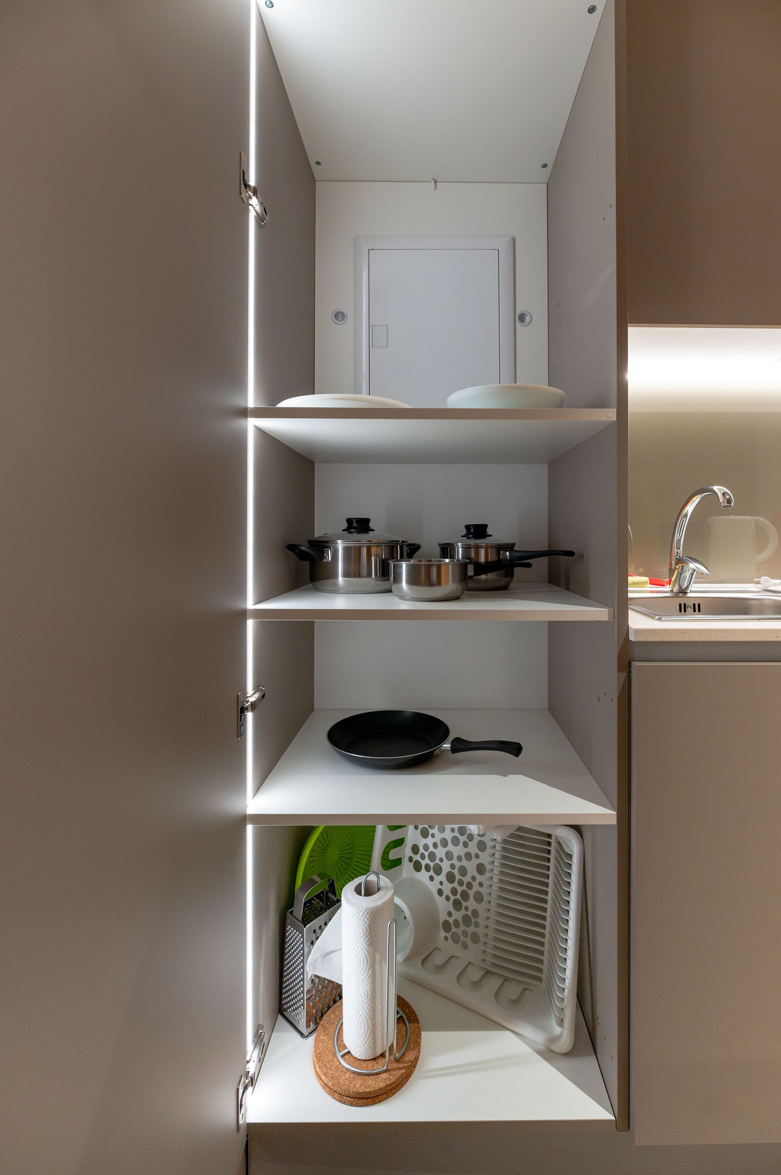 Una cocina con armarios blancos, un lavamanos y diferentes utensilios de cocina.