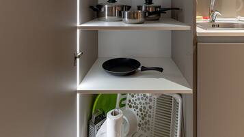 Una cocina con armarios blancos, un lavamanos y diferentes utensilios de cocina.