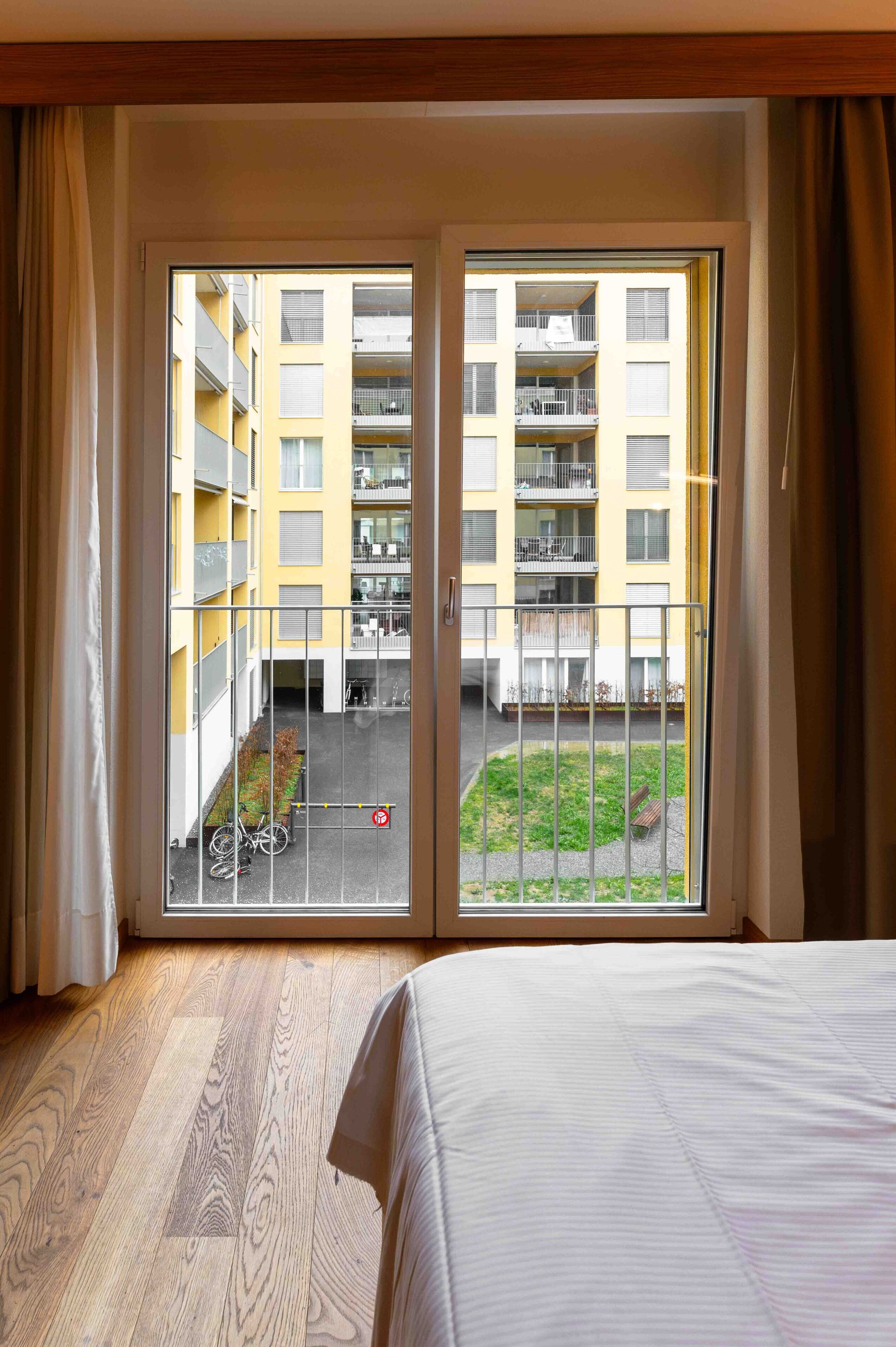 A hotel room with a large sliding glass door leading to a courtyard with a bicycle and a small garden.