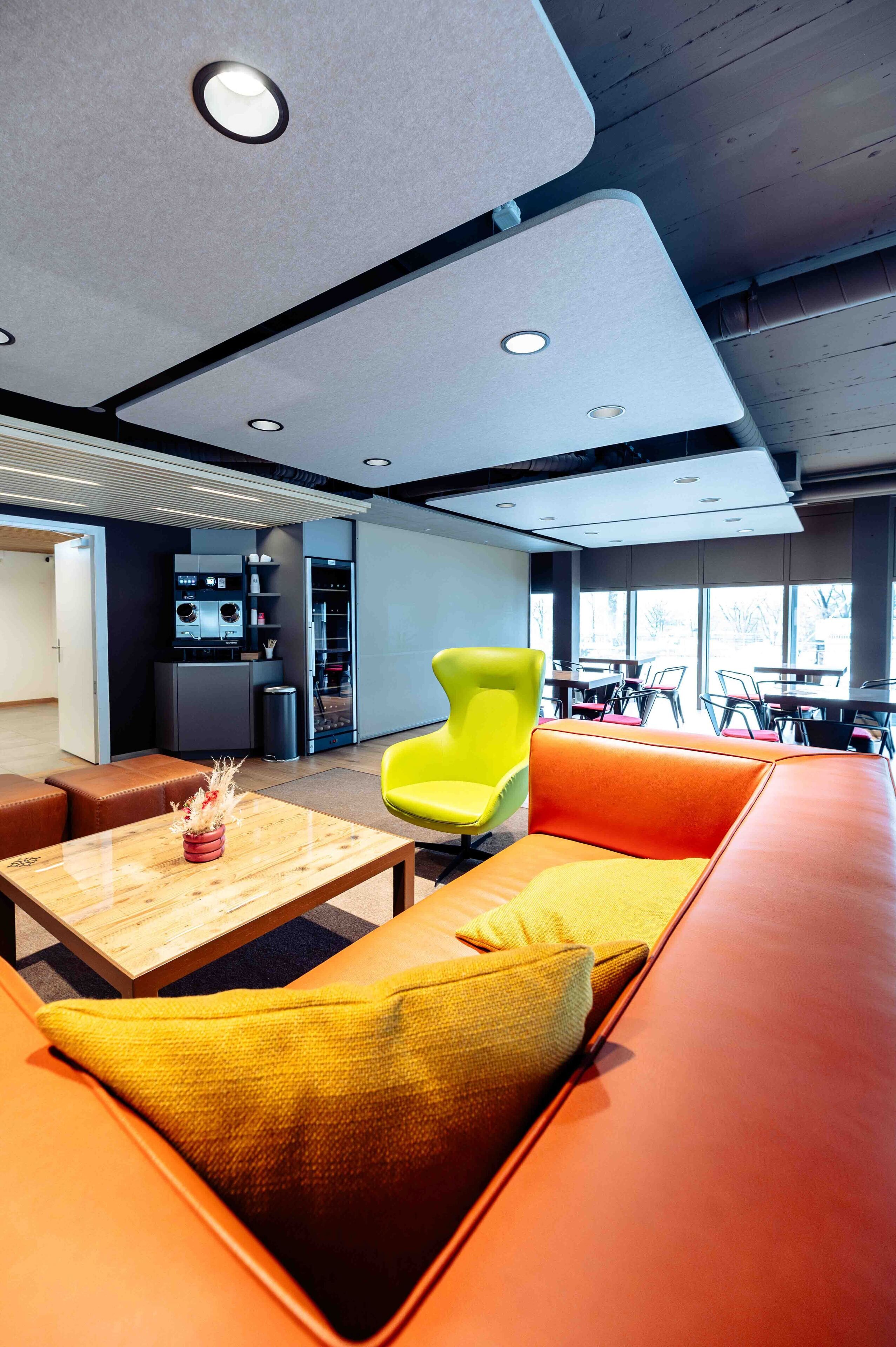 Een moderne lounge met zitplaatsen, een koffieapparaat en een automaat.
