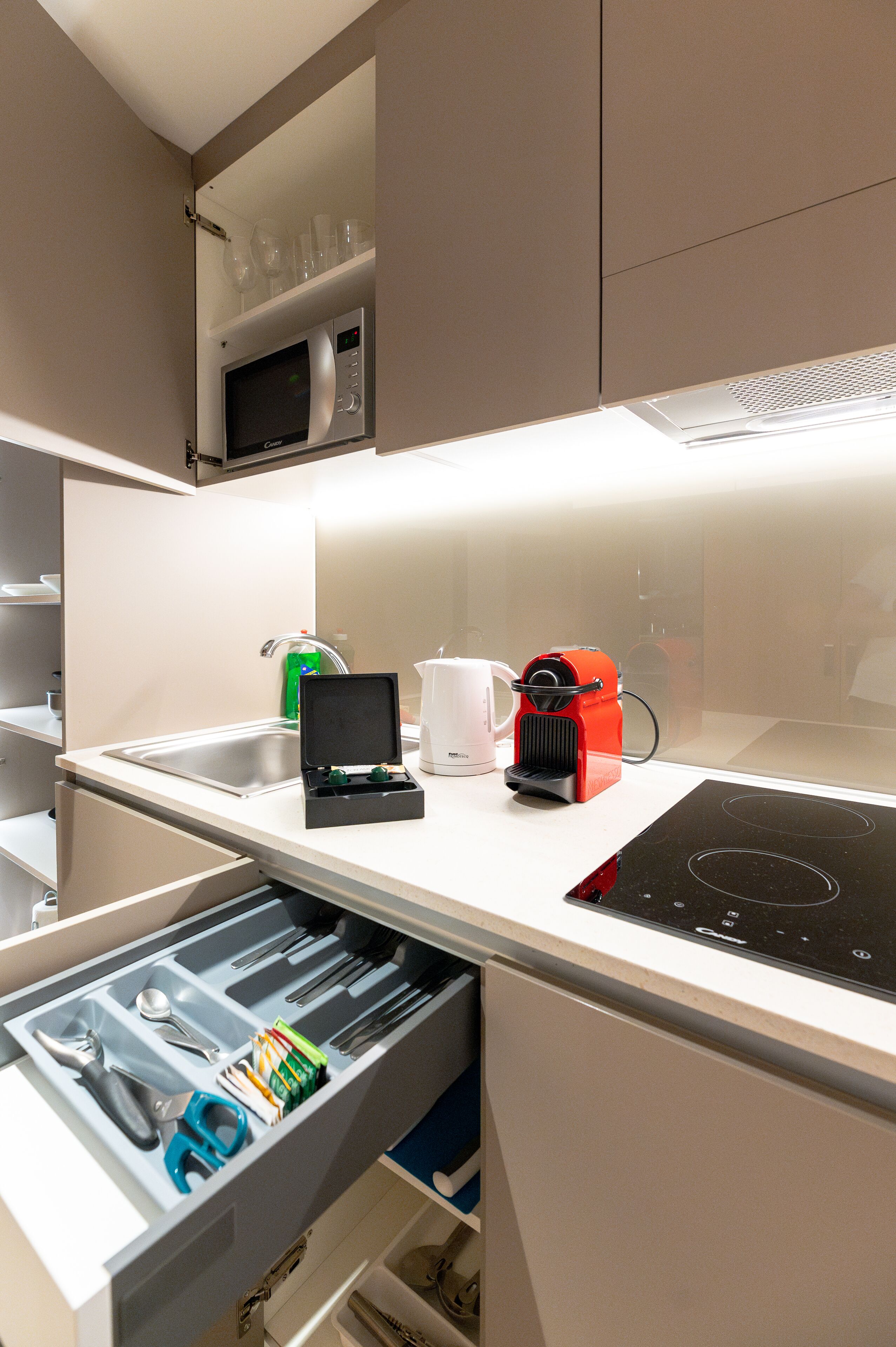 Eine moderne Küche mit integriertem Mikrowellenherd, Wasserkocher und Kaffeemaschine.