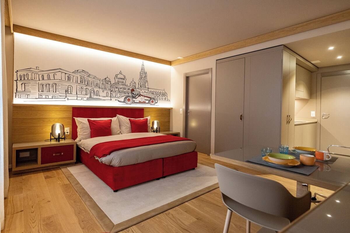 A modern bedroom with a bed, bedside tables, a desk, and a wardrobe.