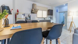 A modern kitchen with a dining area, featuring a wooden table, black chairs, and a lamp. - Fanta Sea Apartment (Larnaca)
