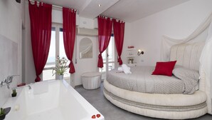 A modern bathroom with a bathtub, a round bed with a red pillow, and a vanity with a mirror. - Historic Seafront Villa, 10 meters from the sea on the Tyrrhenian coast (Rosignano Solvay-Castiglioncello)