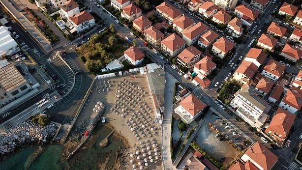 An aerial view of a coastal residential area with houses, a beach, and a parking lot. - Historic Seafront Villa, 10 meters from the sea on the Tyrrhenian coast (Rosignano Solvay-Castiglioncello)