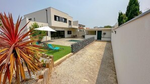 A modern two-story house with a covered patio, a swimming pool, and a well-maintained garden.
