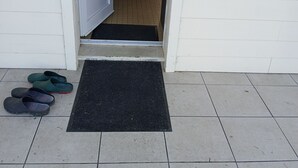 A doorway leading to a room with a tiled floor and a black mat at the entrance.