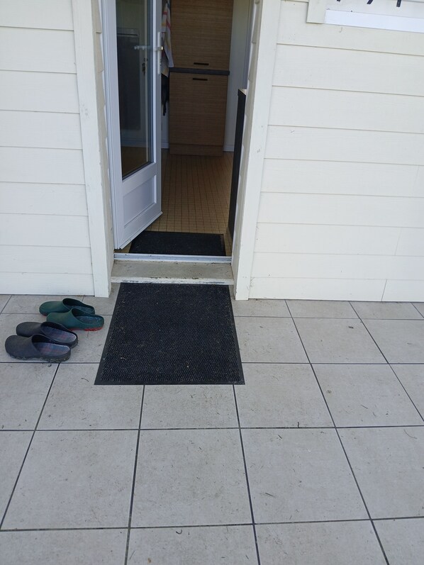 A doorway leading to a room with a tiled floor and a black mat at the entrance.