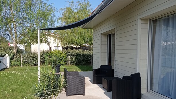 A patio area with outdoor furniture, a potted plant, and a house with a covered porch.