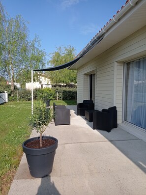 A patio area with outdoor furniture, a potted plant, and a house with a covered porch.