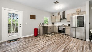Una cocina moderna con electrodomésticos de acero inoxidable, un cubo de basura rojo y piso de madera.
