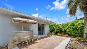 Un patio con zona de bar, mobiliario exterior y vistas a exuberante vegetación.