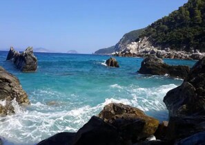 Litoral rochoso com águas turquesa translúcidas e grandes pedras.