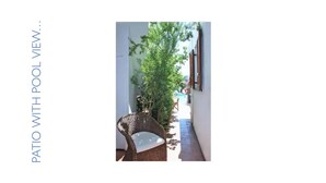 A narrow corridor with a wicker chair, a potted plant, and a view of a pool area.