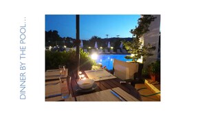 An outdoor dining area with a pool in the background.