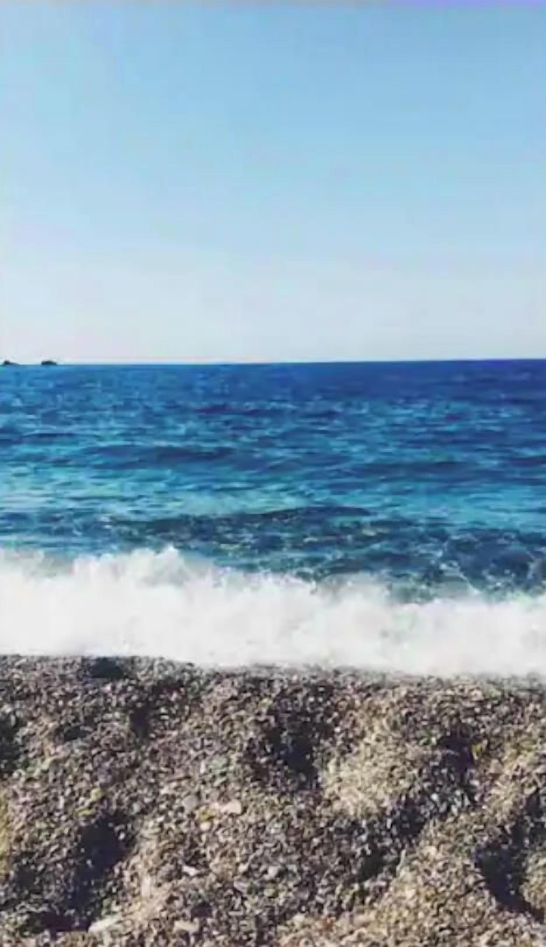 A beach with waves crashing onto a rocky shore.