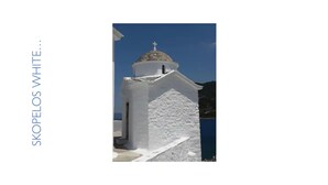 A white church with a dome and cross, located near a body of water.