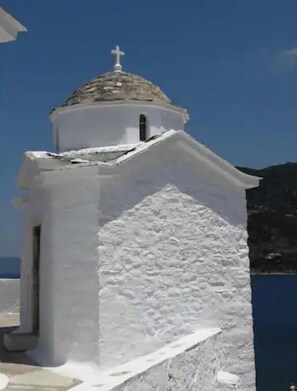 Eine weiße Kirche mit Kuppel und Kreuz in der Nähe eines Gewässers.