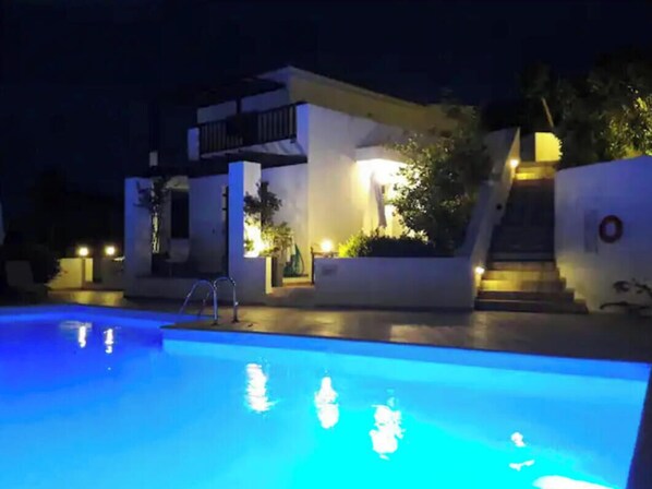Vista noturna de um edifício moderno com piscina.