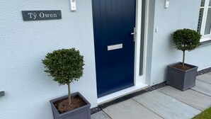 A house with a dark blue door, a nameplate reading "Ty Owen," and two potted trees on the sidewalk. - Ty Owen (Bangor)