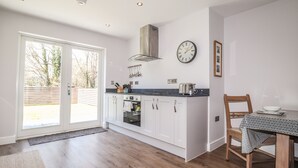 A modern kitchen with white cabinets, a built-in oven, a toaster, and a clock on the wall. - Ty Owen (Bangor)