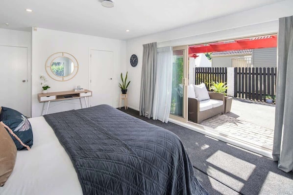 Una camera da letto con un letto, un comodino, uno specchio e vista su un patio esterno.