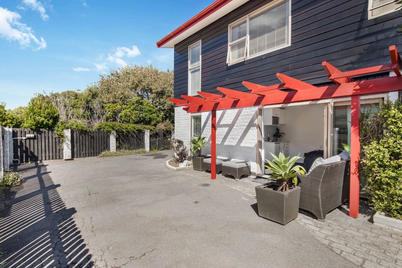 A residential property with a covered patio area, outdoor seating, and a fenced backyard.
