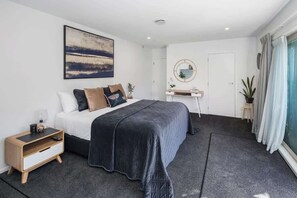 Ein modernes Schlafzimmer mit Bett, Nachttisch und Schreibtisch mit Spiegel.