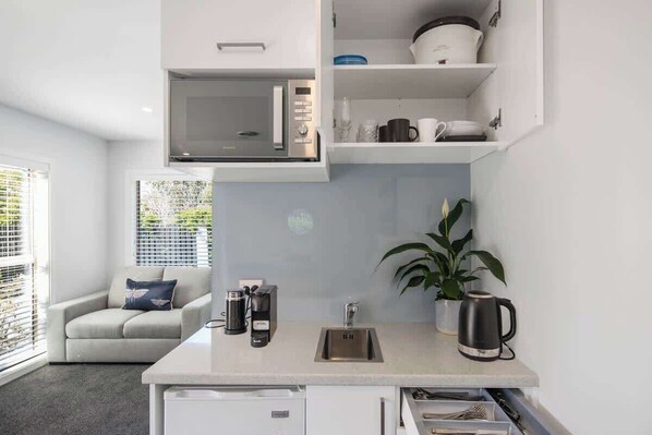 A compact kitchen with a built-in microwave, a sink, and a coffee maker.