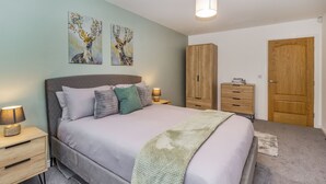 A bedroom with a bed, nightstands, a wardrobe, and two paintings on the wall.