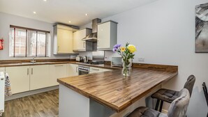 A modern kitchen with wooden countertops, a built-in stove, and a dining area with a wooden table and two chairs.