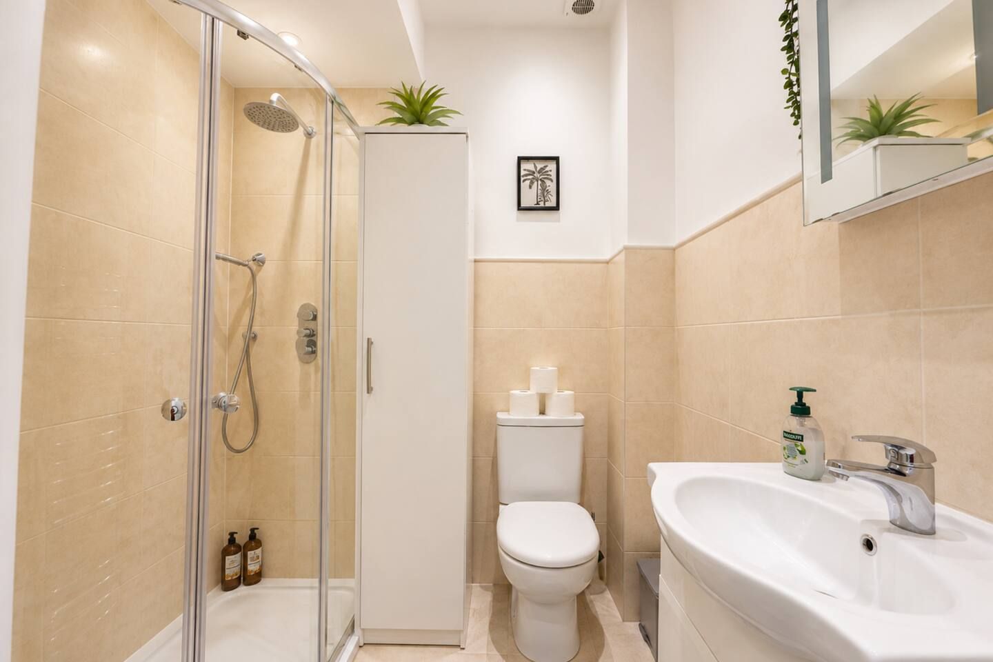 A modern bathroom with a glass-enclosed shower, a toilet, and a sink with a mirror above.