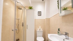 Een moderne badkamer met een douchecabine van glas, een toilet en een wastafel met spiegel.