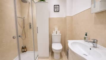 A modern bathroom with a glass-enclosed shower, a toilet, and a sink with a mirror above.