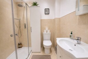 Une salle de bain moderne avec une douche à parois de verre, des toilettes et un lavabo avec un miroir au-dessus.