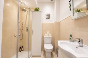 A modern bathroom with a glass-enclosed shower, a toilet, and a sink with a mirror above.