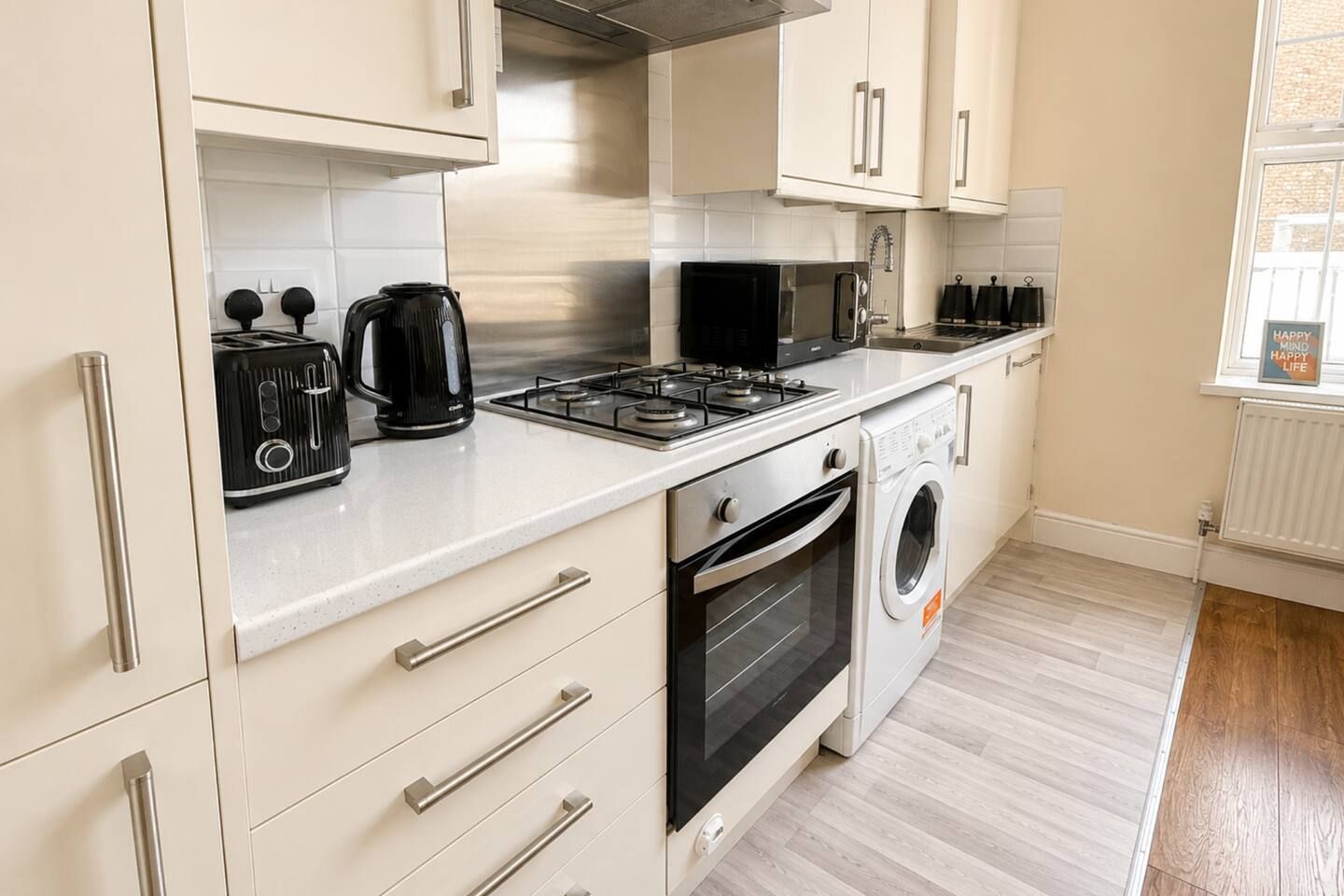 A modern kitchen with stainless steel appliances, a built-in oven, and a washing machine.
