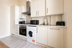 A compact kitchen with a built-in oven, microwave, and a front-loading washing machine.