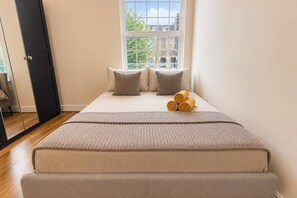 A bedroom with a bed, pillows, a blanket, and a window.