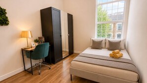 Een slaapkamer met een bed, een bureau, een stoel en een kledingkast.