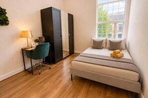 A bedroom with a bed, a desk, a chair, and a wardrobe. - Cozy 2-bedroom Apt in Shepherds near Westfield (London)