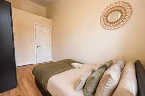 Une chambre à coucher avec un lit, des oreillers, une couverture, une porte et un élément décoratif mural.