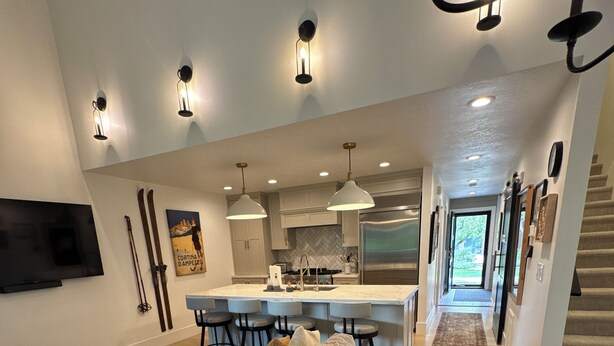 A modern kitchen with a central island, pendant lighting, and a dining area with bar stools.