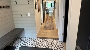 A hallway with a patterned floor, a bench, and a door on the right.
