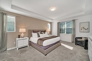 A bedroom with a large bed, bedside tables, a dresser, and a window with blinds.